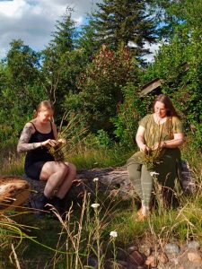 Zwei Frauen flechten einen Korb im Wald